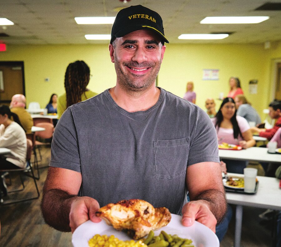 A volunteer serves a plate of food at a Salvation Army community kitchen