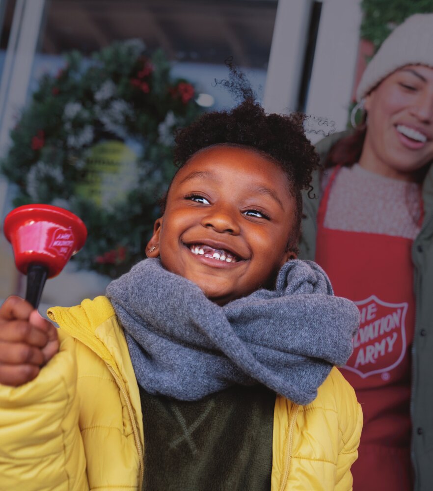 A child rings a Red Kettle bell during the holiday season