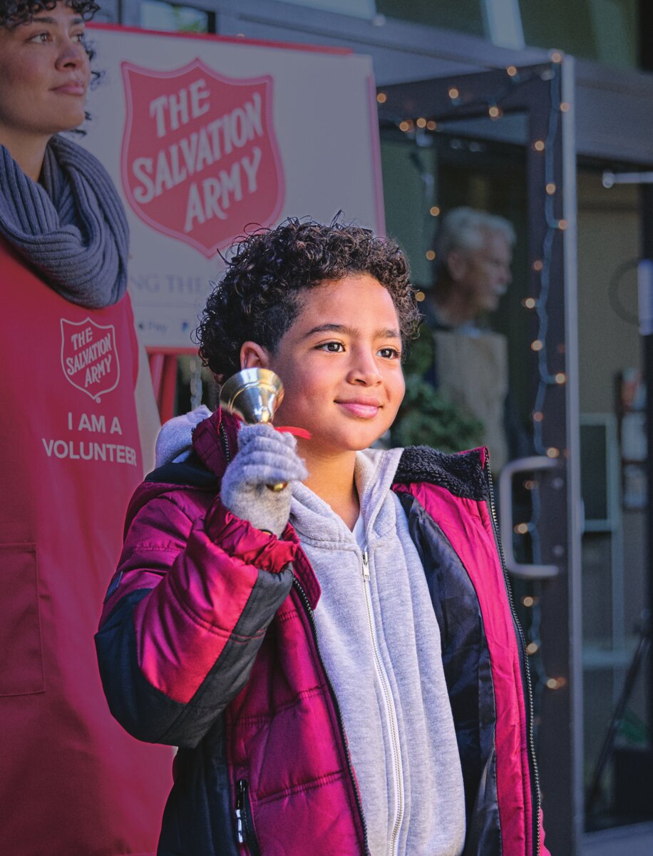 A young Salvation Army volunteer rings a Red Kettle bell